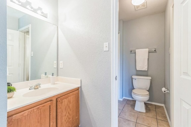 bathroom with tile patterned floors, vanity, toilet, a textured wall, and baseboards