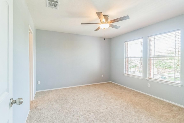 carpeted spare room featuring a ceiling fan and baseboards
