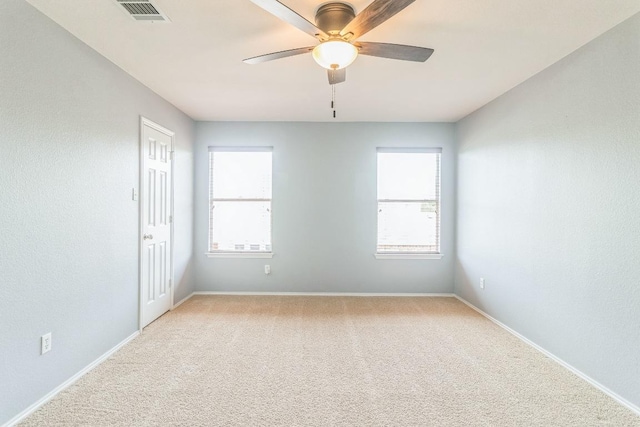 spare room featuring ceiling fan, light carpet, and baseboards