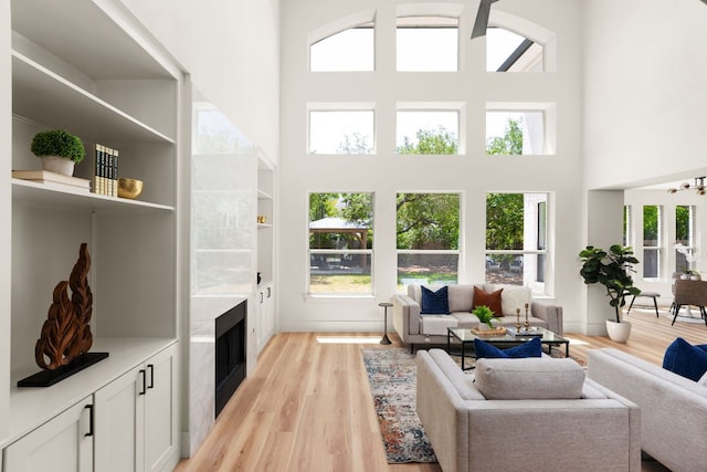 6909 Larue Belle Cv, Austin, TX 78739 - living room featuring a high ceiling, light wood finished floors, and a tiled fireplace