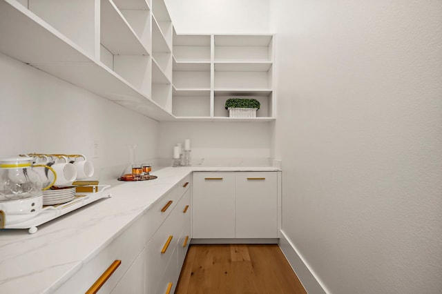 kitchen with light wood-style floors, open shelves, light stone counters, and white cabinets