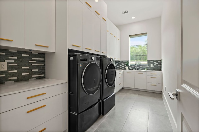 laundry room with washer and clothes dryer, cabinet space, and light tile patterned flooring