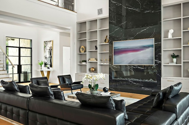 living room featuring stairway, built in features, a towering ceiling, and wood finished floors