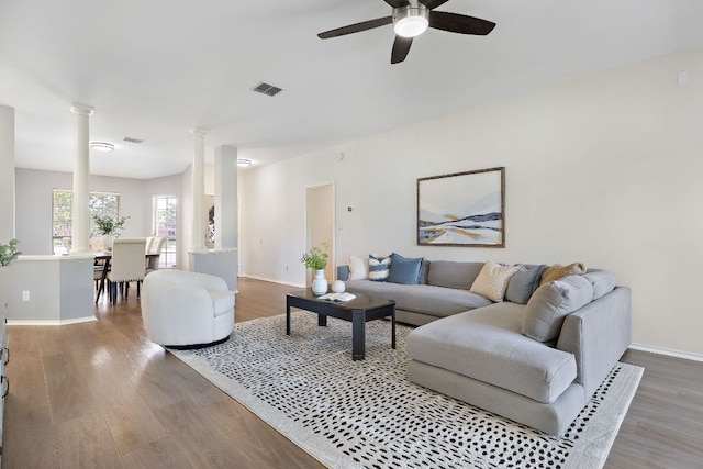 living room featuring decorative columns, wood finished floors, ceiling fan, and baseboards
