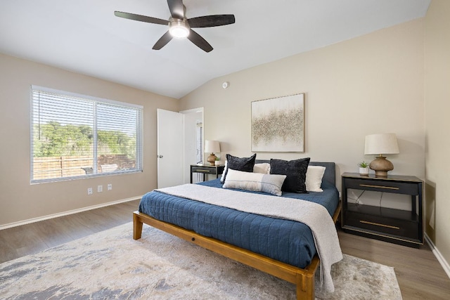 bedroom with wood finished floors, lofted ceiling, baseboards, and ceiling fan