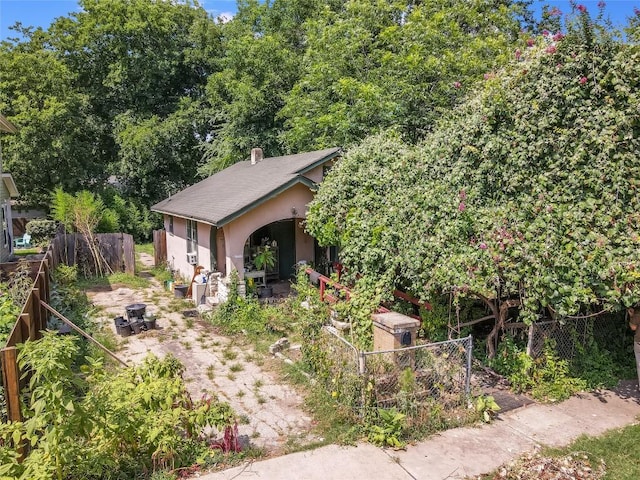 view of property hidden behind natural elements with fence and stucco siding