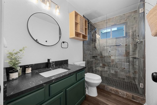full bathroom featuring toilet, wood finished floors, a stall shower, and vanity