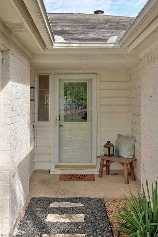 property entrance featuring a shingled roof