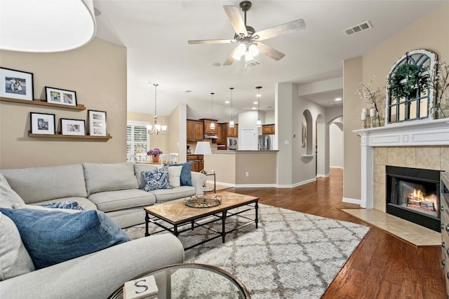 240 Maeves Way, Austin, TX 78737 - living room with dark wood-style floors, ceiling fan, arched walkways, a tiled fireplace, and baseboards