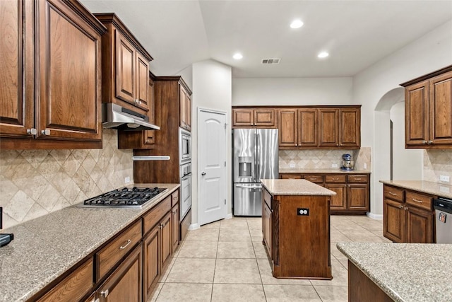 240 Maeves Way, Austin, TX 78737 - kitchen with appliances with stainless steel finishes, under cabinet range hood, tasteful backsplash, arched walkways, and light tile patterned flooring