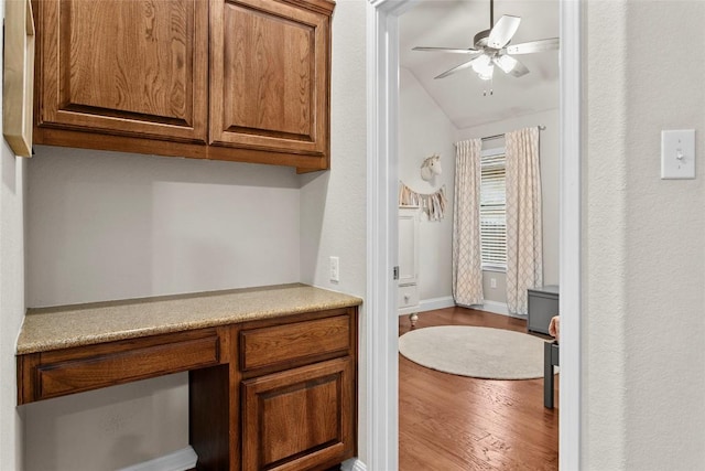 240 Maeves Way, Austin, TX 78737 - kitchen featuring wood finished floors, ceiling fan, brown cabinets, light countertops, and vaulted ceiling