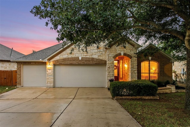 240 Maeves Way, Austin, TX 78737 - view of front facade featuring an attached garage, driveway, stone siding, fence, and a shingled roof