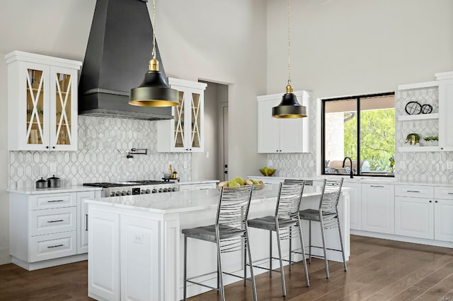 kitchen with tasteful backsplash, a towering ceiling, a kitchen island, dark wood-type flooring, and custom exhaust hood