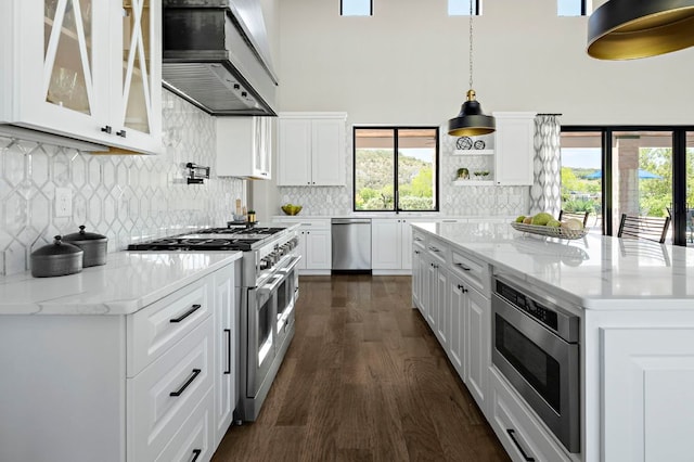 kitchen featuring stainless steel appliances, premium range hood, a high ceiling, dark wood-type flooring, and white cabinets