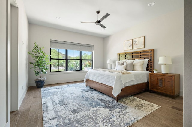 bedroom featuring wood finished floors, baseboards, and a ceiling fan
