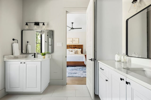 ensuite bathroom featuring two vanities, a ceiling fan, and tile patterned flooring