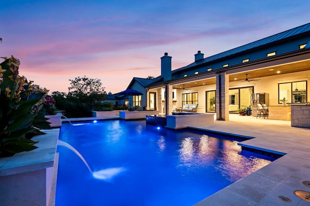 pool at dusk featuring a ceiling fan, a patio, an outdoor pool, and outdoor lounge area