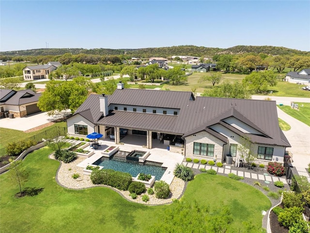 811 Wade Rd, New Braunfels, TX 78132 - rear view of property with a chimney, a standing seam roof, a patio area, a pool with connected hot tub, and a residential view