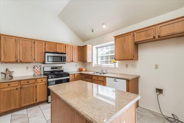 kitchen featuring stainless steel appliances, a sink, brown cabinetry, lofted ceiling, and decorative backsplash