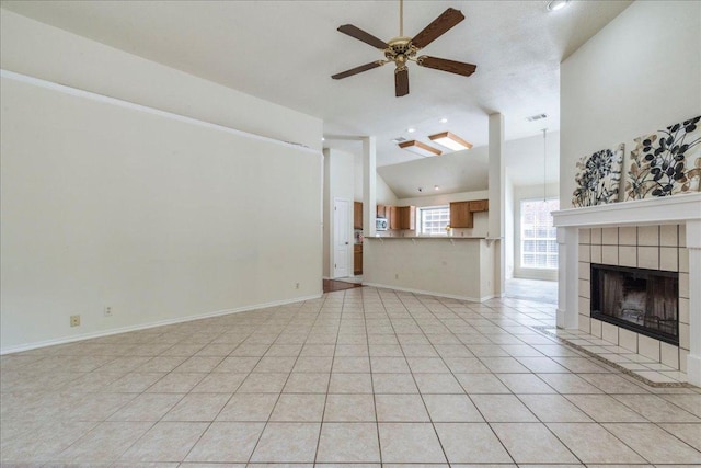 unfurnished living room featuring lofted ceiling, ceiling fan, a tile fireplace, light tile patterned flooring, and recessed lighting