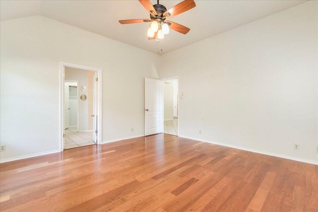 empty room featuring wood finished floors, ceiling fan, baseboards, and lofted ceiling