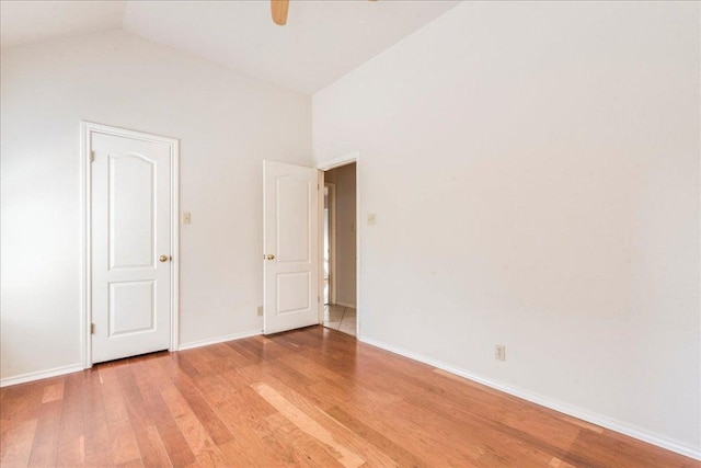empty room featuring light wood finished floors, baseboards, lofted ceiling, and ceiling fan