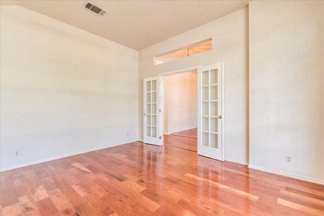 empty room with french doors, wood finished floors, and baseboards