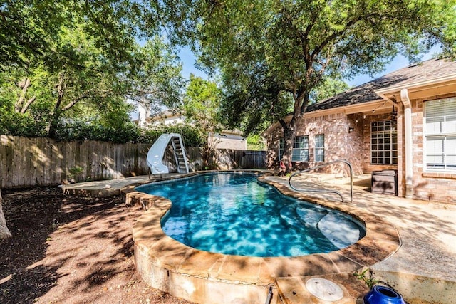 view of swimming pool with a water slide, a fenced backyard, and a patio area