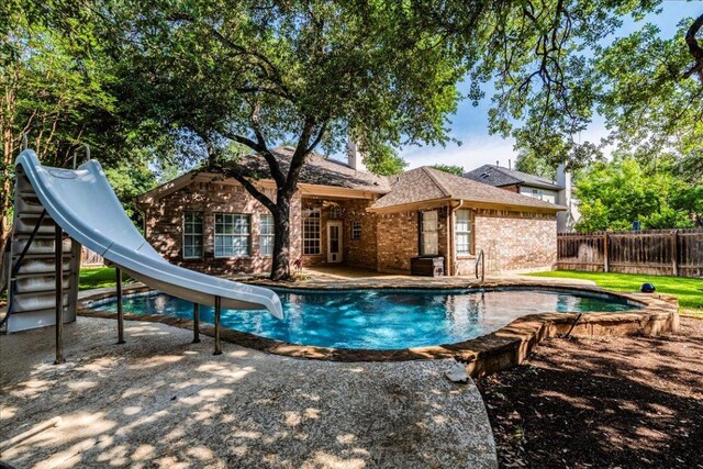 view of pool featuring a water slide, fence, and a patio