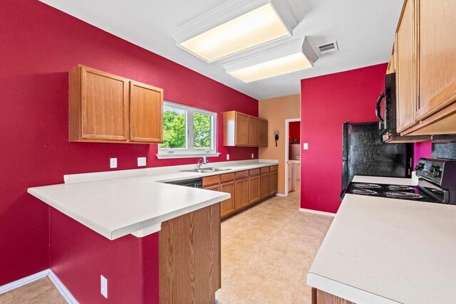 kitchen featuring black / electric stove, washer and clothes dryer, a sink, and light countertops