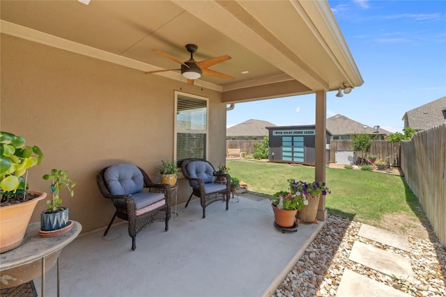 view of patio featuring ceiling fan, an outdoor structure, and a storage unit