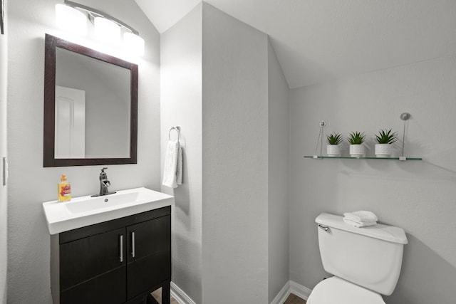 bathroom with vaulted ceiling, vanity, toilet, and baseboards