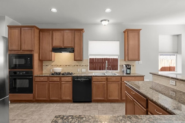426 Valona Loop, Round Rock, TX 78681 - kitchen with black appliances, range hood, brown cabinetry, and tasteful backsplash