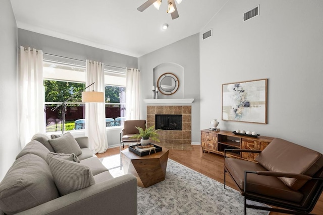 living room with ceiling fan, lofted ceiling, a fireplace, wood finished floors, and baseboards