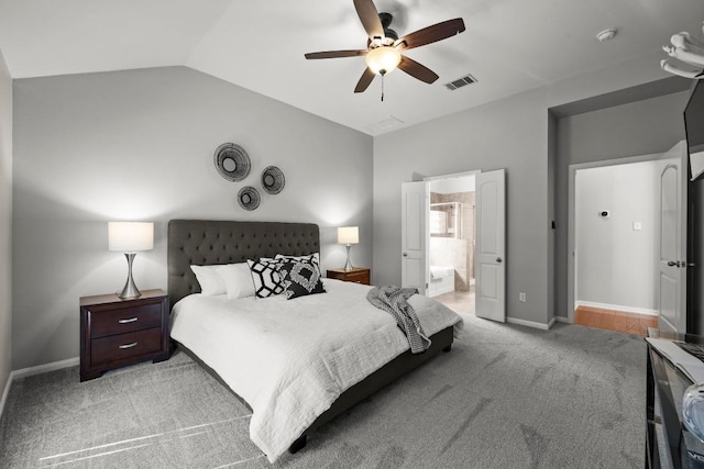 bedroom with light colored carpet, vaulted ceiling, ceiling fan, ensuite bath, and baseboards