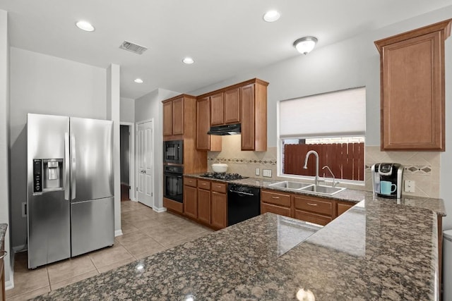 426 Valona Loop, Round Rock, TX 78681 - kitchen with black appliances, under cabinet range hood, brown cabinets, light tile patterned floors, and tasteful backsplash