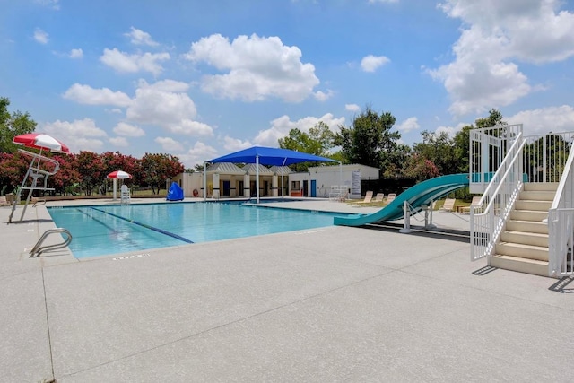 community pool featuring a water slide, a patio, and fence