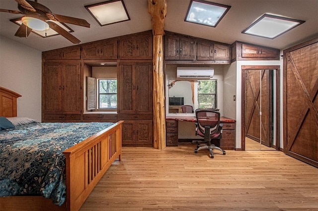 914 Sand Hills Rd, Red Rock, TX 78662 - bedroom featuring lofted ceiling, light wood-type flooring, an AC wall unit, multiple windows, and built in study area