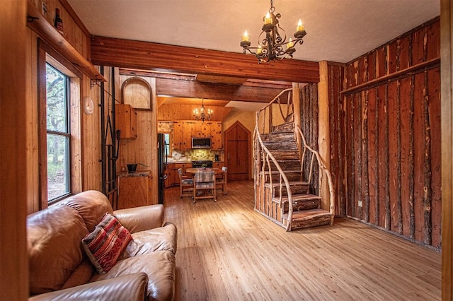 914 Sand Hills Rd, Red Rock, TX 78662 - living room with a chandelier, light wood finished floors, stairs, and wooden walls