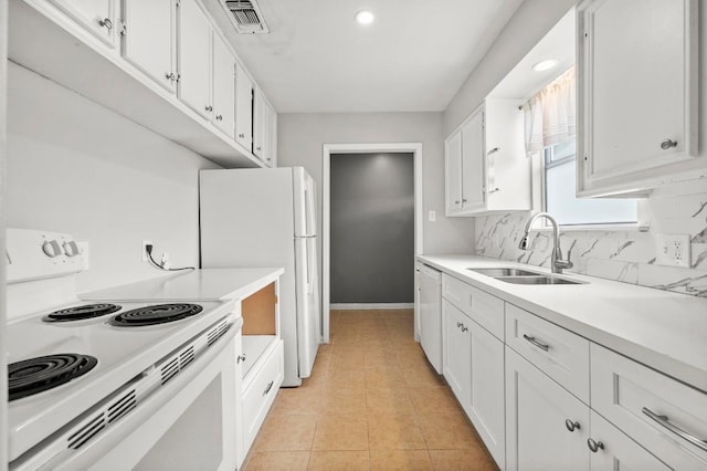 kitchen featuring white appliances, a sink, white cabinets, light countertops, and recessed lighting