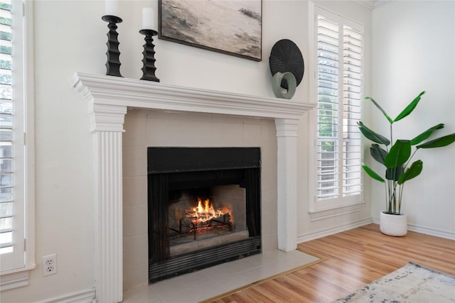 detailed view of a tiled fireplace, wood finished floors, and baseboards
