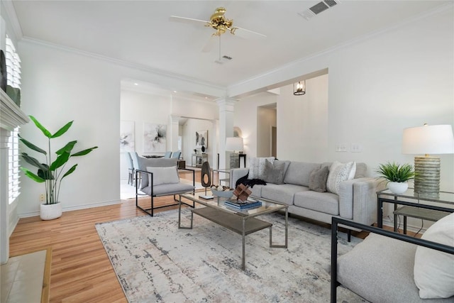 living room with a ceiling fan, wood finished floors, ornamental molding, decorative columns, and baseboards