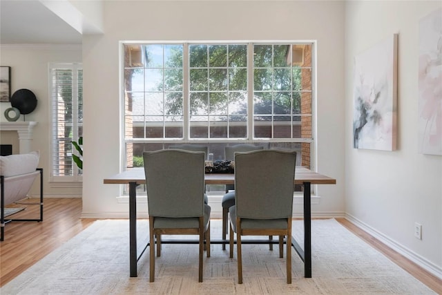 dining room featuring wood finished floors, crown molding, baseboards, and a fireplace