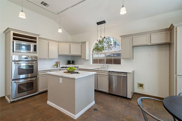 kitchen featuring appliances with stainless steel finishes, a sink, vaulted ceiling, light countertops, and hanging light fixtures