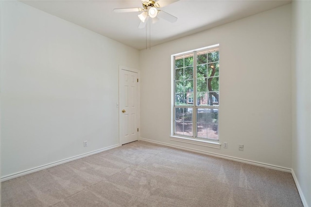 carpeted spare room with ceiling fan and baseboards