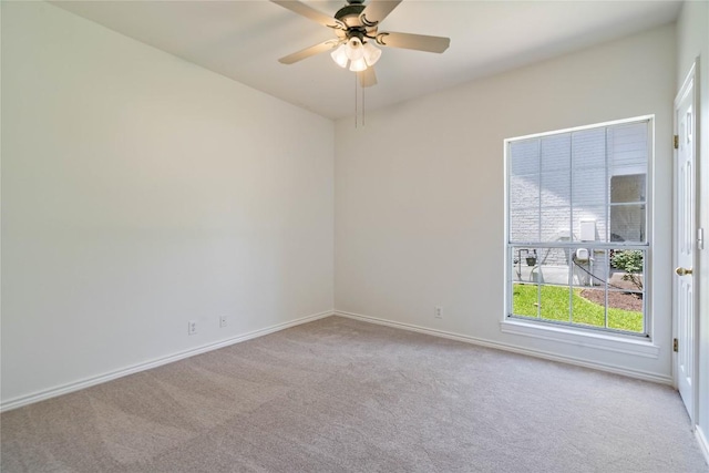 carpeted spare room featuring baseboards and ceiling fan
