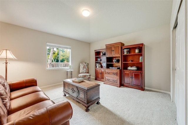 living area featuring light carpet and baseboards