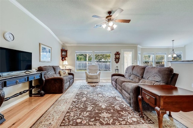 living room featuring wood finished floors, ornamental molding, a ceiling fan, vaulted ceiling, and a textured ceiling