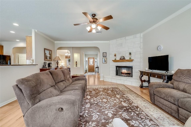 living room with arched walkways, light wood-style floors, crown molding, a ceiling fan, and recessed lighting