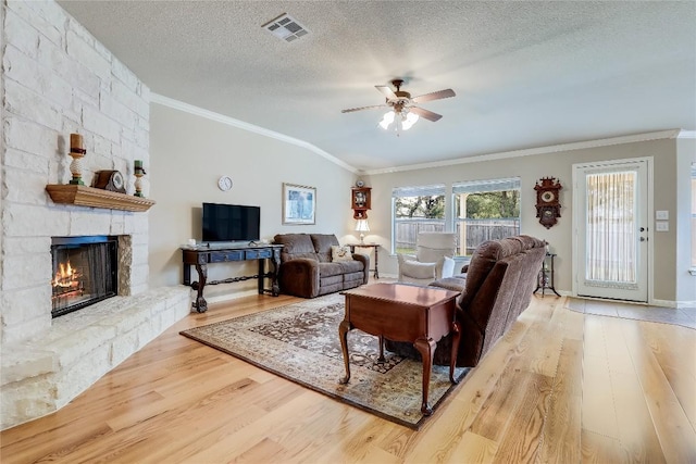 living area with wood finished floors, a ceiling fan, crown molding, a fireplace, and a textured ceiling